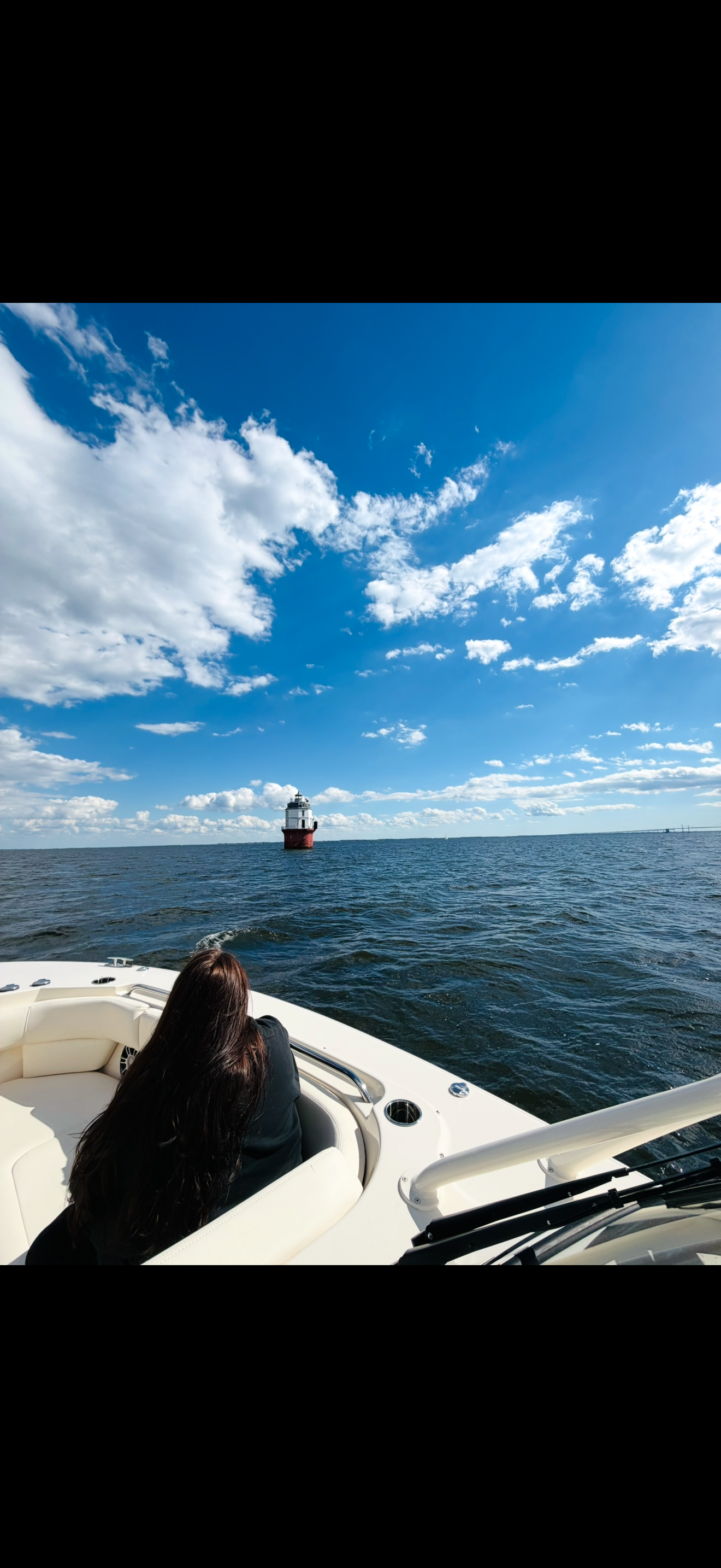 Sammi Griswold on the boat with a Chesapeake Bay lighthouse in the distance